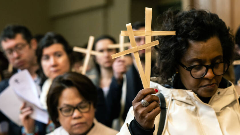 A procession of people walking at Easter holding palm crosses.