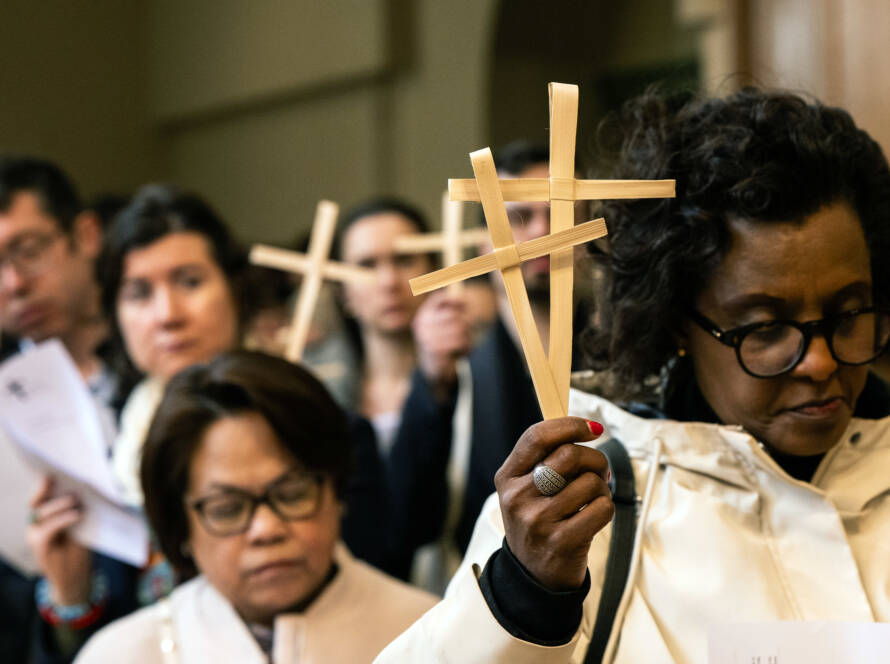 A procession of people walking at Easter holding palm crosses.